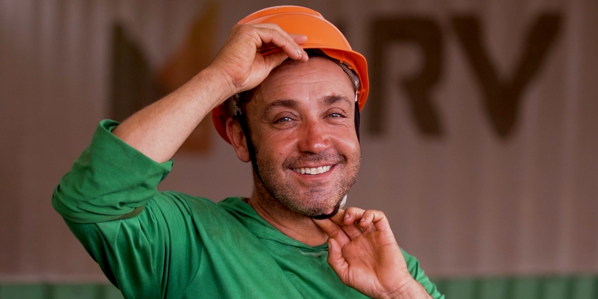 Funcionário Éder Bergamo sorrindo enquanto coloca capacete em obra da MRV